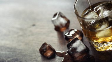 Bir cam ile buzlu viski. Küpleri buz ahşap bir masa üzerinde bir