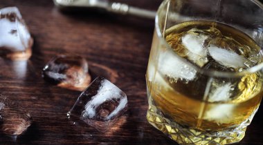 Bir cam ile buzlu viski. Küpleri buz ahşap bir masa üzerinde bir