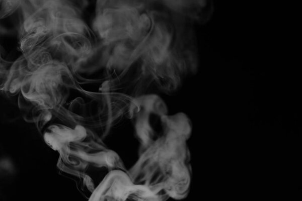White smoke on a black background. Texture of smoke. Clubs of white smoke on a dark background for overlay