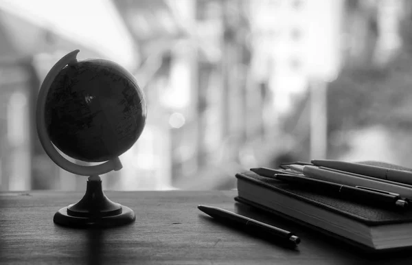 En penna på skrivbordet med liten jordglob — Stockfoto