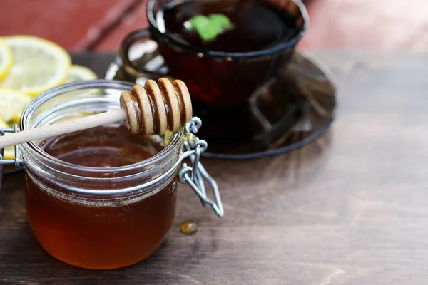 Fresh honey with a cup of black tea — Stock Photo, Image