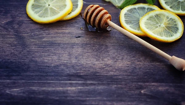Мед и лимон. Медовая палочка и ломтики нарезанного лимона на вуу — стоковое фото