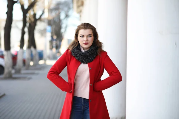 漂亮的女孩，穿着红色的外套，在城里散步 — 图库照片