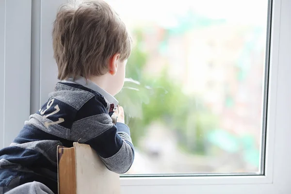 The little boy is reading a book. The child sits at the window a — Stock Photo, Image