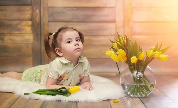 Un petit enfant avec un bouquet de tulipes jaunes. Un garçon avec un cadeau — Photo