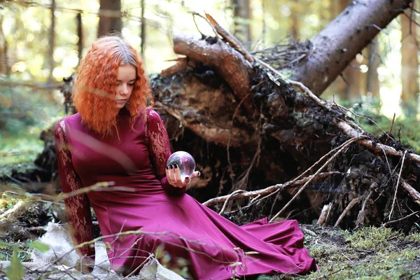 La sorcière rousse tient un rituel avec une boule de cristal — Photo