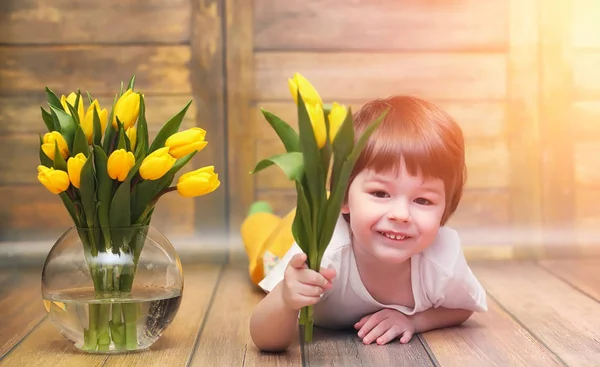 Uma criança pequena com um buquê de tulipas amarelas. Um rapaz com um dom — Fotografia de Stock