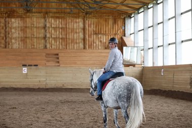 İnsanlar ahşap bir arenada at eğitiminde.
