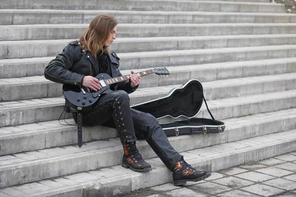 Rock guitarist on the steps. A musician with a bass guitar in a