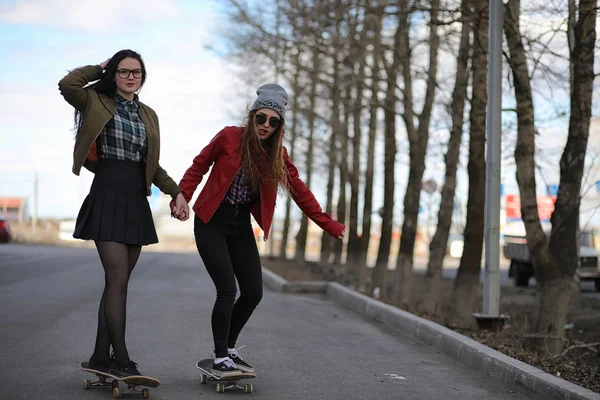 Una giovane hipster sta cavalcando uno skateboard. Ragazze amiche f — Foto Stock