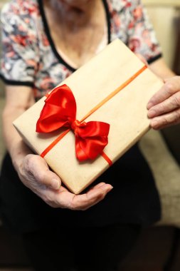 Büyükanne ellerinde kırmızı fiyonklu hediye kutusu