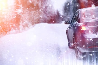 Bir karla kaplı yolda araba duruyor