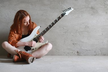 Kızıl saçlı kız bir elektro gitar ile. Rock müzisyen GIR