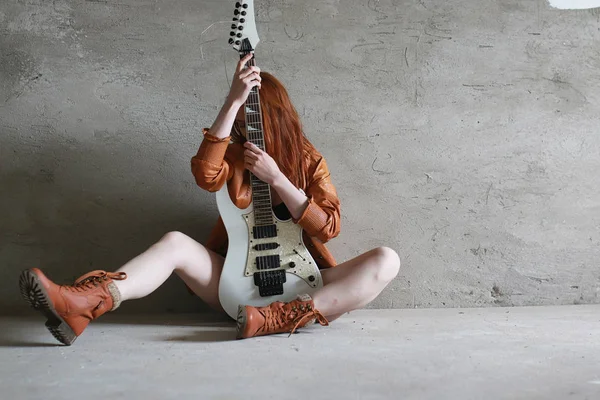 Ung rødhåret pige med en elektrisk guitar. Rock musiker gir - Stock-foto