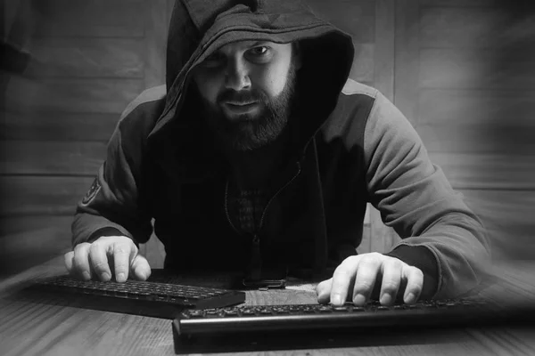 El hacker en el capó se sienta y trabaja detrás de la computadora — Foto de Stock