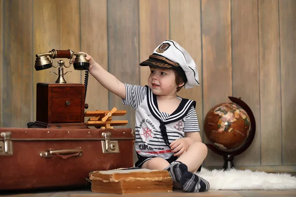 Un enfant dans un intérieur rétro et un vieux téléphone est assis sur le sol . — Photo