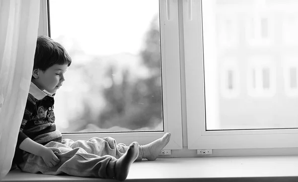 The little boy is reading a book. The child sits at the window a — Stock Photo, Image