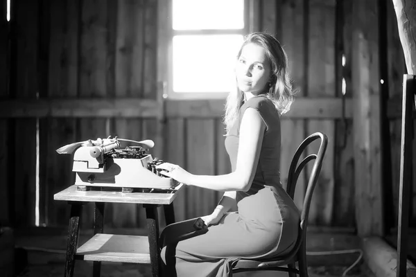 A girl prints on an old typewriter — Stock Photo, Image
