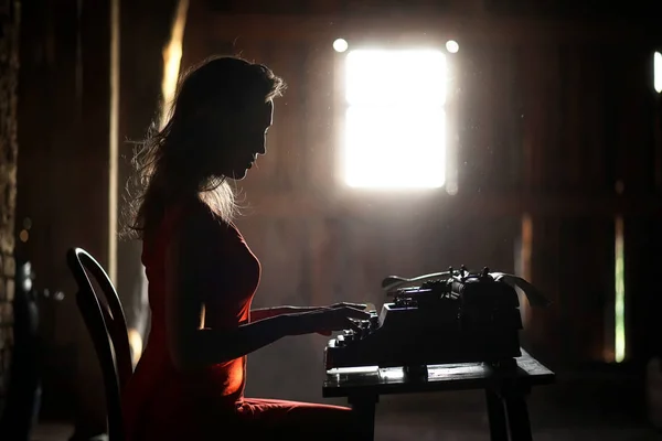 A girl in retro style prints on an old typewriter — Stock Photo, Image