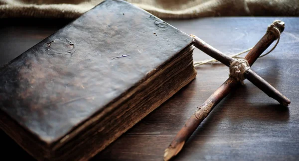 Antiguo libro religioso sobre una mesa de madera. Una cruz religiosa atada ingenio — Foto de Stock