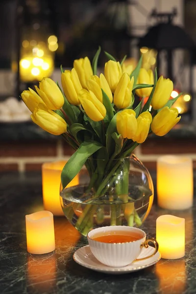 A bouquet of yellow tulips in a vase in the interior of a retro