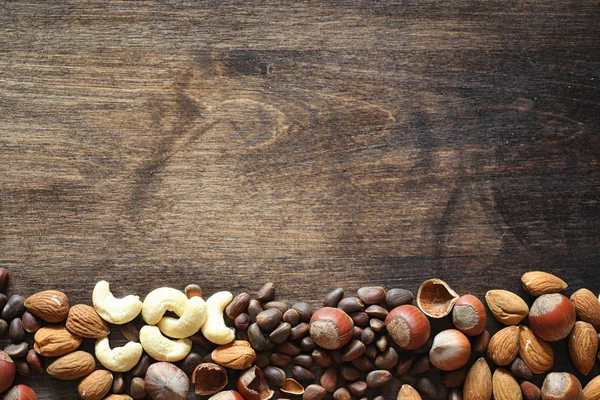 Olika nötter på ett träbord. Ceder, cashew, hasselnöt, walnu — Stockfoto