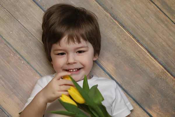 Bir buket Sarı laleler ile küçük bir çocuk. Bir çocuk bir hediye ile — Stok fotoğraf