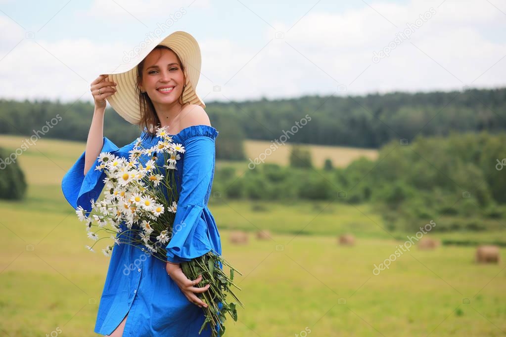 Young cute girl in a hat in a field at sunset