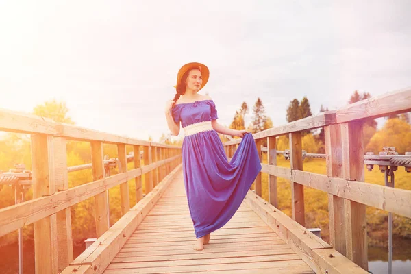 Young beautiful girl in dresses on nature. A girl in a hat walks — Stock Photo, Image