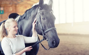 İnsanlar ahşap bir arenada at eğitiminde.