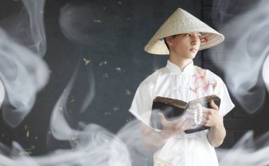 Bir kitap ile bir kimono Asya adam dua ediyor