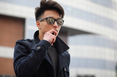 Asya genç adam sokakta Sigara