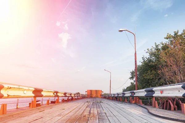 Holzbrücke am Ufer des Flusses. eine Holzstraße mit Säulen. Pfanne — Stockfoto