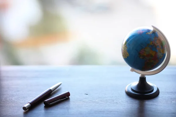 A pen on the desk and a small globe — Stock Photo, Image