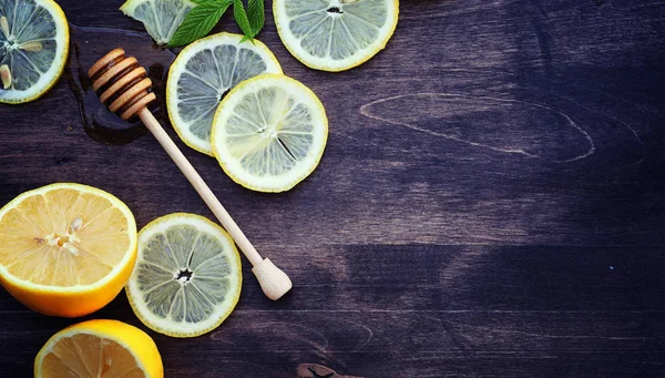 Мед и лимон. Медовая палочка и ломтики нарезанного лимона на вуу — стоковое фото