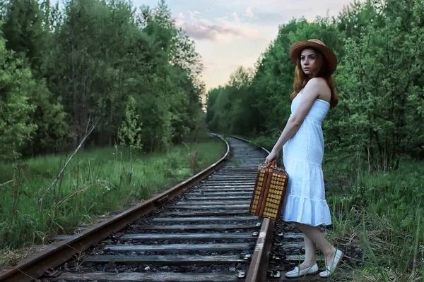 Fille dans une robe blanche et une valise en osier marchant sur les rails — Photo