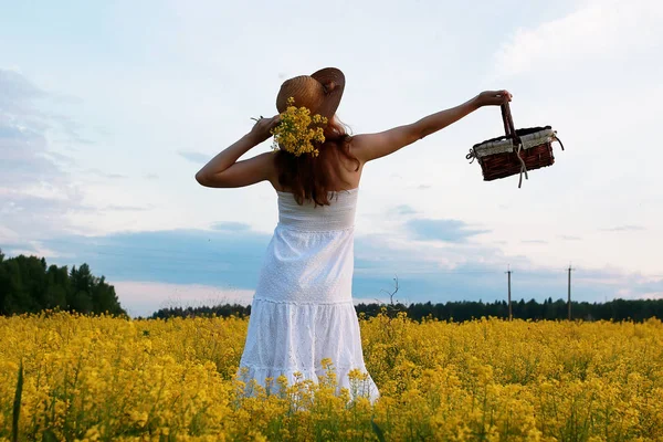 Ragazza in cappello di paglia in un campo di fiori gialli in fiore — Foto Stock