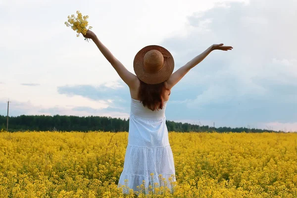 Meisje met strohoed in een veld van gele bloemen bloeiend — Stockfoto