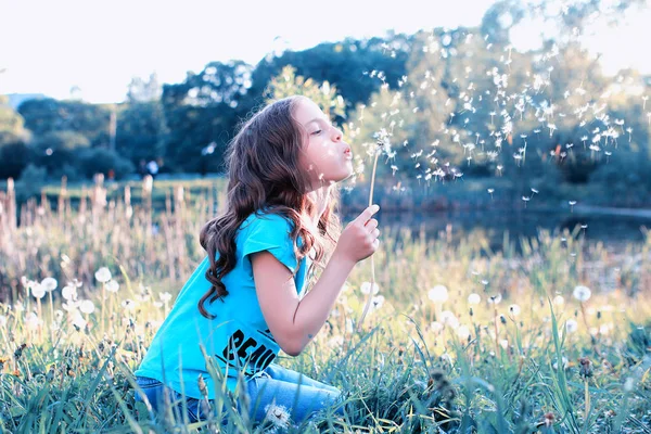 Dospívající dívka foukání z květina Pampeliška semena na jaře parku — Stock fotografie