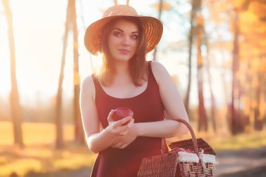 Parkta bir yürüyüş üzerinde şapkalı bir kız. Bir kızla bir sepet yürüyüş