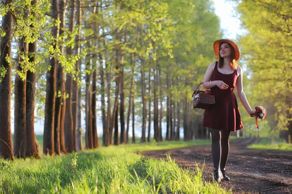 Una ragazza con un cappello mentre passeggia nel parco. Una ragazza con un cesto a piedi — Foto Stock