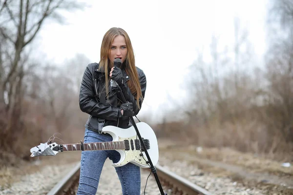 Uma menina músico de rock em uma jaqueta de couro com uma guitarra — Fotografia de Stock