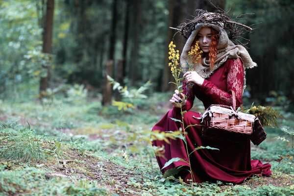 The red-haired witch holds a ritual with a crystal ball in the forest