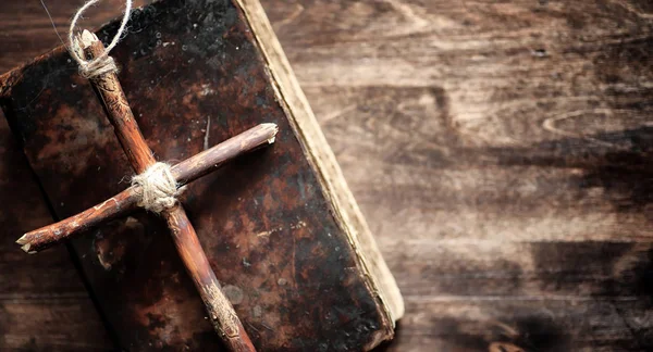 Livro velho religioso em uma mesa de madeira. Uma cruz religiosa amarrado sagacidade — Fotografia de Stock