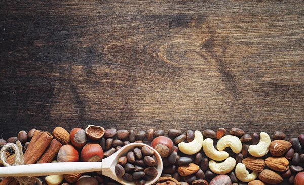 Verschillende noten op een houten tafel. Cedar, cashewnoten, hazelnoten, walnu — Stockfoto