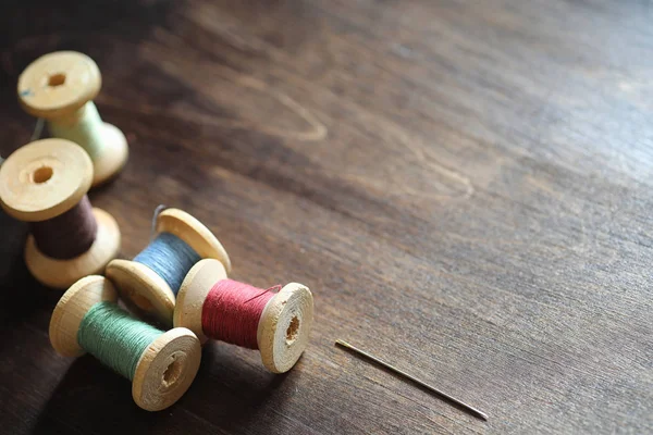 Jahitan benang pada latar belakang kayu. Set dari thread di bobbins — Stok Foto