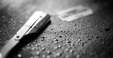 Tehlikeli bir ustura ve masanın üzerinde metal bir bıçak. Mens tıraş 