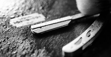 Tehlikeli bir ustura ve masanın üzerinde metal bir bıçak. Mens tıraş 