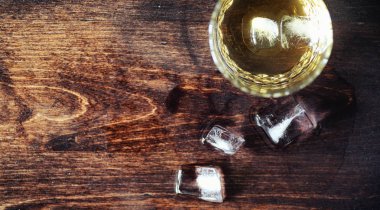 Bir cam ile buzlu viski. Küpleri buz ahşap bir masa üzerinde bir