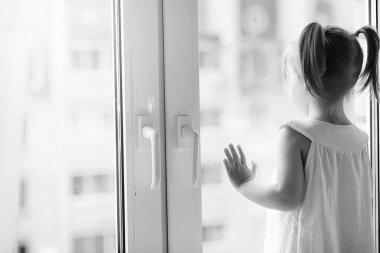 Küçük bir kız kenarında oturuyor. Bir buket çiçek